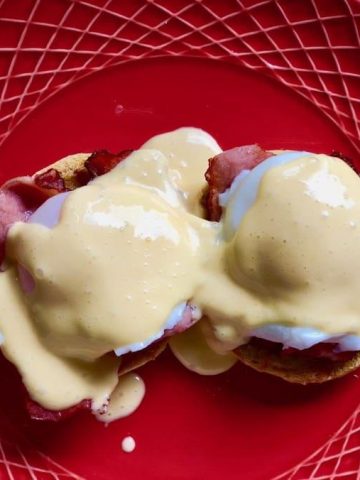 Eggs benedict and quick hollandaise on a red dinner plate