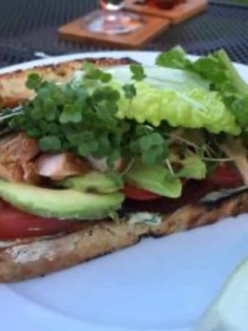 Hot smoked salmon club sandwich assembled on a white plate