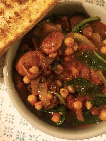 Spanish chorizo stew in a small tapas dish with crusty bread on the side