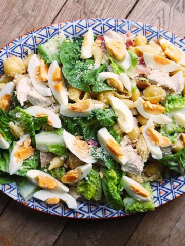 Chicken caesar pasta salad on large blue, white and orange patterned serving platter