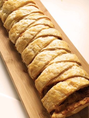 Spanish-flavoured sausagemeat plait on wooden board with knife
