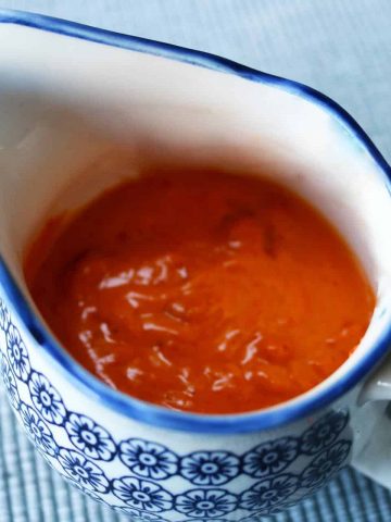 Red pepper and paprika hollandaise sauce in a blue and white floral jug