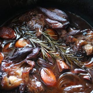 Close up of lamb shanks in black casserole pot
