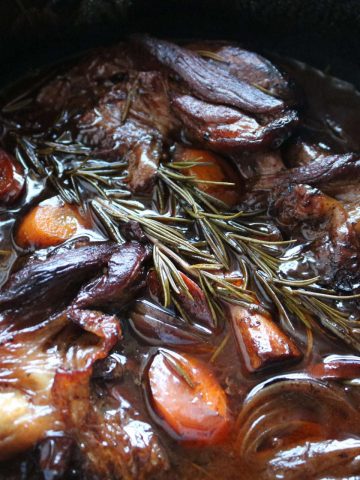 Close up of lamb shanks in black casserole pot