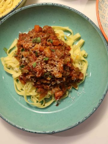 Bowls of lamb, tomato and oregano ragu on top of tagliatelle pasta