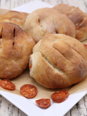 Side view of 5 chorizo bread buns with sliced chorizo on the side