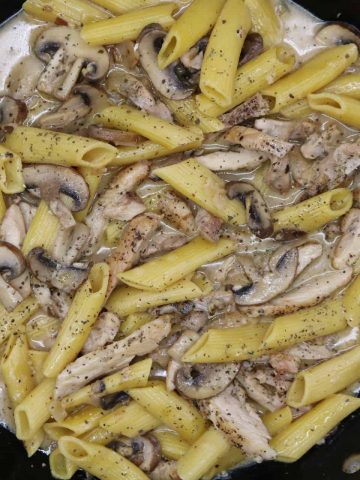 Overhead view of creamy chicken and mushroom pasta in large frying pan