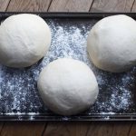 3 balls of pizza dough on baking tray