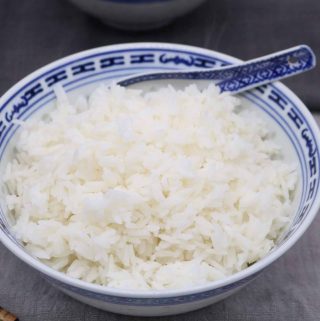 Jasmine rice in oriental bowl with spoon and chopsticks