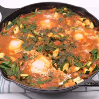 Side view of spicy moroccan eggs in black skillet