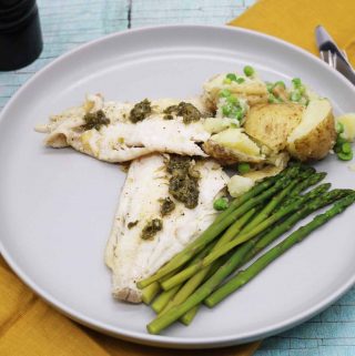 Grey dinner plate with haddock, potatoes, peas and asparagus