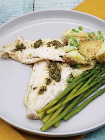 Grey dinner plate with haddock, potatoes, peas and asparagus