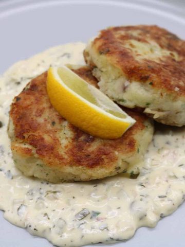 Close view of fishcakes with tartare sauce on grey dinner plate