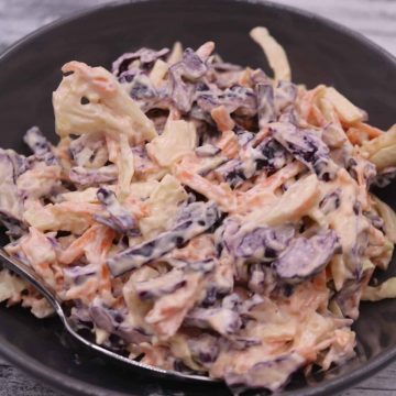 Close up of red and white coleslaw in a grey bowl with spoon