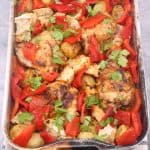 Side view of chicken thighs with romesco traybake in roasting tin