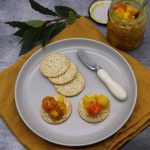 Jar of piccalilli and grey plate with poppy seed crackers with cheese and piccalilli