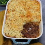 Cheesy beef bourguignon pie in Staub dish with portion of potatoes removed