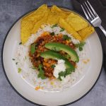 Mexican turkey chilli with rice, tortilla crisps, avocado, coriander and soured cream in bowl