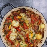 sausages, potatoes, tomatoes, onions and peppers in large round casserole