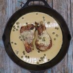 Pork chops in skillet with mustard sauce and capers