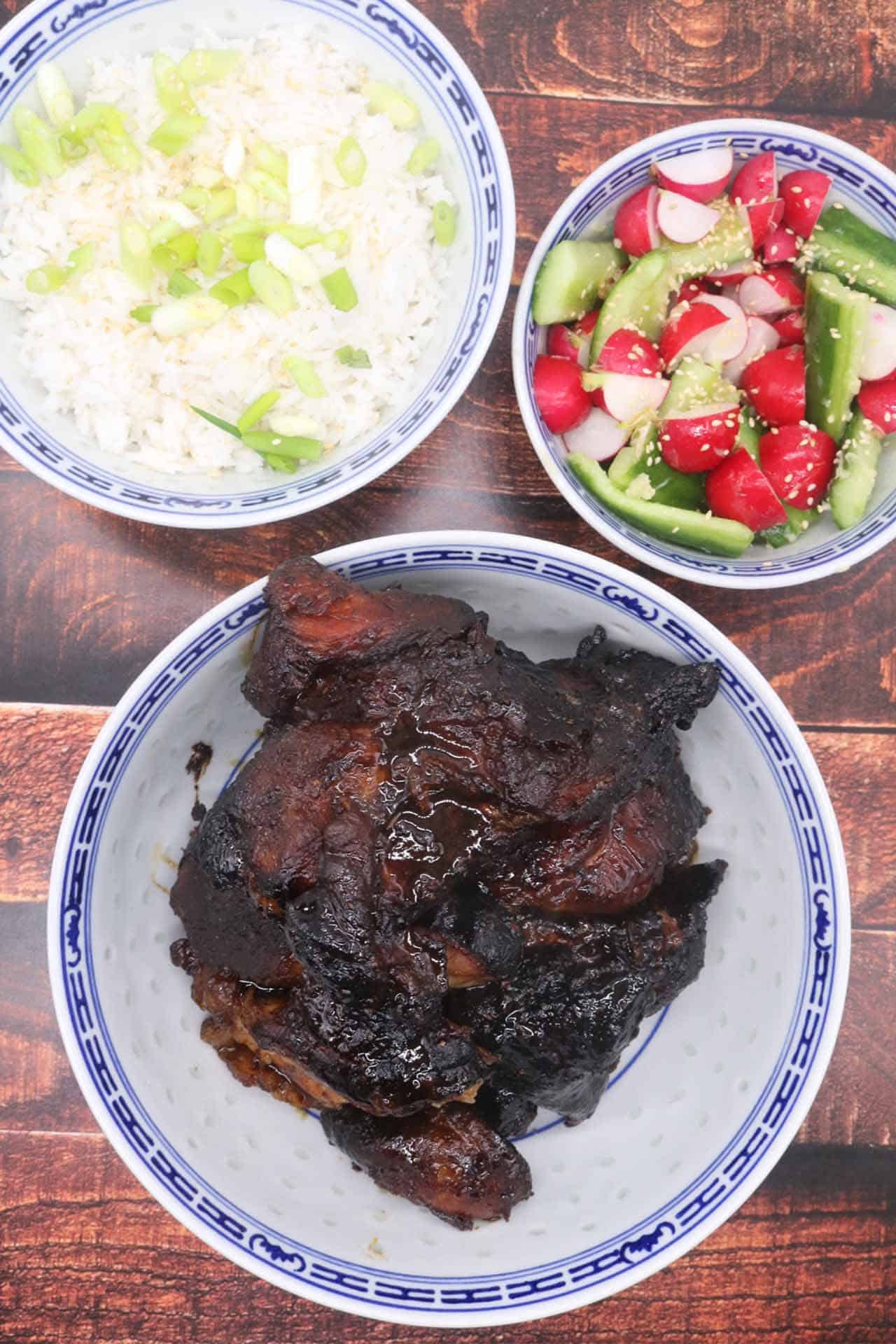 slow roasted hoisin pork shoulder in blue and white bowl with rice and radish and cucumber salad