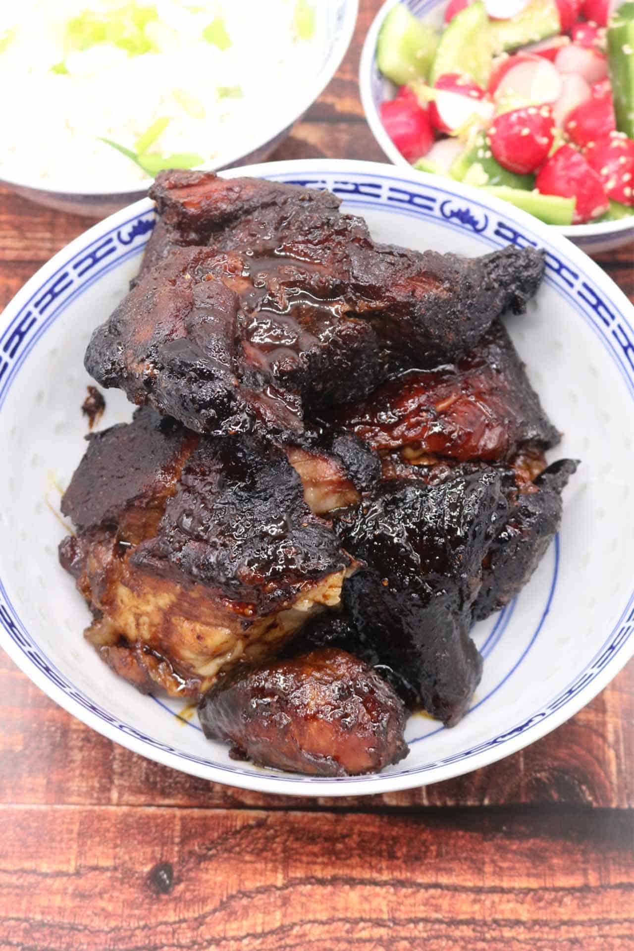 slow roasted hoisin pork shoulder in blue and white bowl with rice and radish and cucumber salad