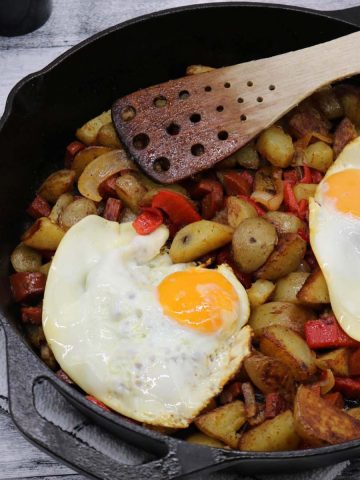 Chorizo and potato hash in skillet with fried eggs on top
