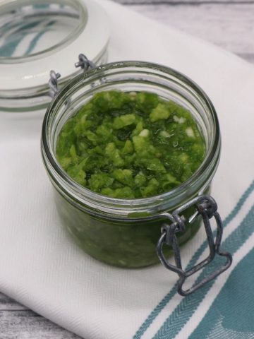 Fresh jalapeño relish in jar on green and white towel