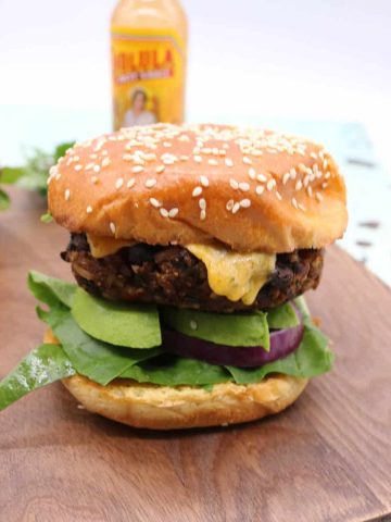 Chilli bean burger in a bun with salad on a wooden board