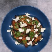 Greek wings with lemon and feta in blue bowl scattered with parsley