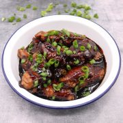 Soy braised chicken wings in round dish scattered with sliced spring onions