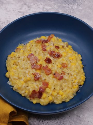 Sweetcorn and bacon risotto in blue bowl with bacon pieces on top