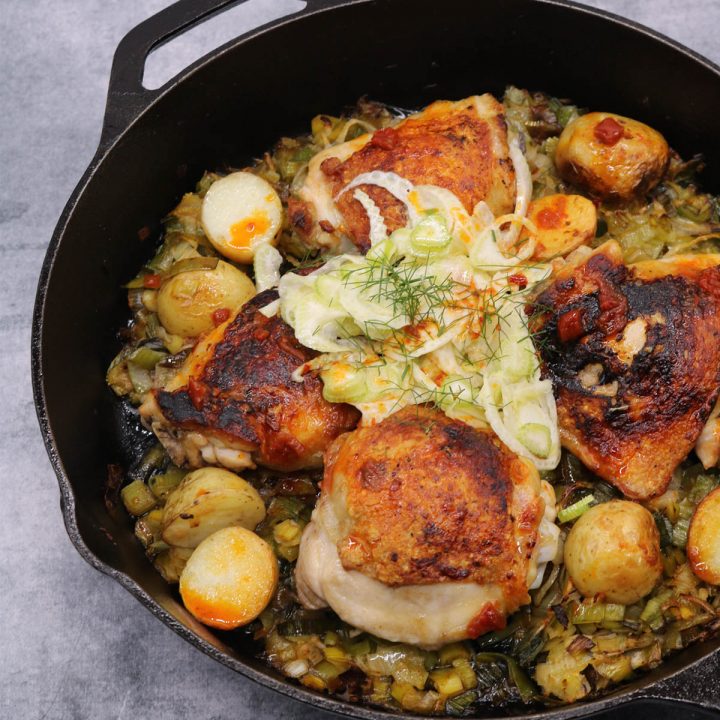 Crispy chicken thighs in skillet with harissa, fennel and potatoes