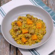 Sausage and squash risotto in grey bowl with green and white towel