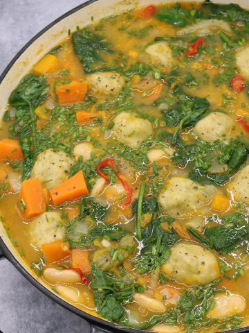 Vegetable stew with cheesy dumplings in large round casserole