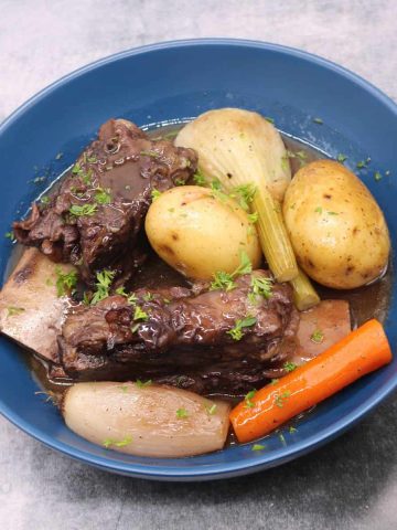 Short ribs of beef in red wine with vegetables in a blue bowl