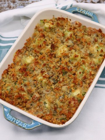Broccoli and stilton crumble in rectangle oven dish sitting on green and white towel