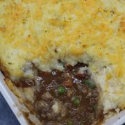 Close up of cottage pie in rectangle oven dish with portion removed