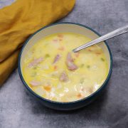 Creamy ham and potato soup in bowl with spoon and yellow napkin