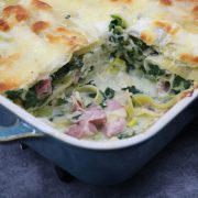 Ham, spinach and mozzarella lasagne in rectangle oven dish with portion removed
