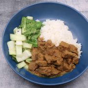 Beef rendang with rice and pak choi in blue bowl
