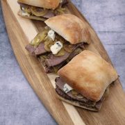 Three Brisket sandwiches with beer onions and blue cheese on a board