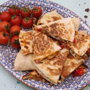 Chicken and chorizo quesadillas sliced in triangles on serving platter with tomatoes