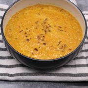 Spice carrot and lentil soup in bowl on top of black and white napkin