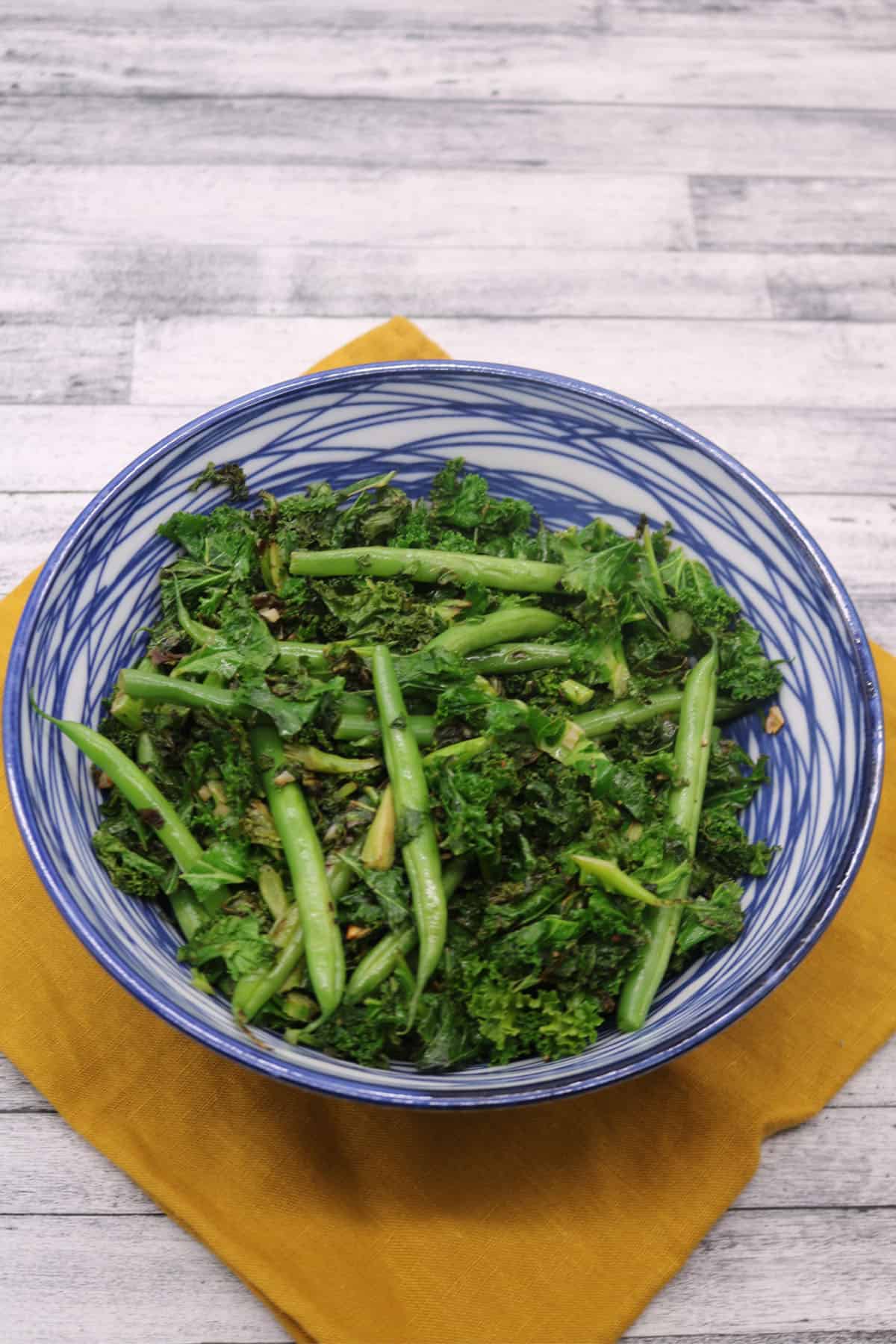 Sauteed kale and green beans in a blue and white bowl