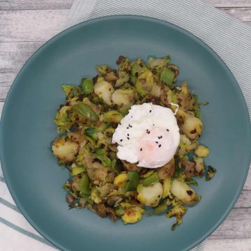 Winter breakfast hash topped with poached egg in green bowl sitting napkin