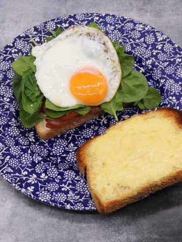 BLT with egg and cheese on a blue and white plate