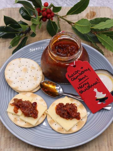 Plate with crackers spread with bacon and cranberry jam and cheese with jar