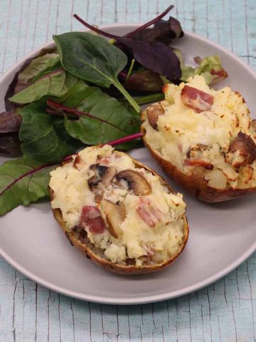 bacon and mushroom baked potato on grey plate with salad leaves