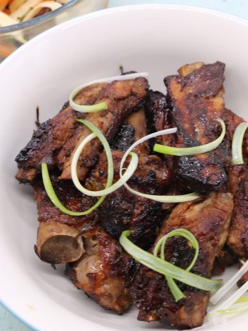 Char sui pork ribs in bowl with spring onions